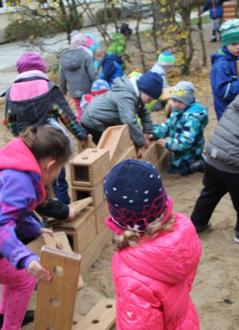 Auf dem Bild sind Kinder, die im Sandkasten aus Bausteinen etwas bauen, zu sehen