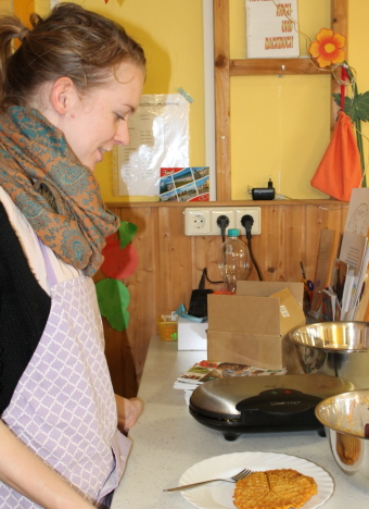 Auf dem Bild ist eine Frau beim Waffelnbacken zu sehen