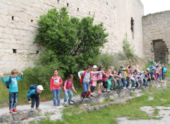 Auf dem Bild sind mehrere Kinder vor einer Burgmauer zu sehen