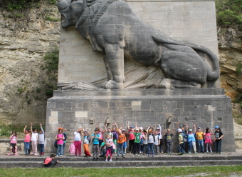 Auf dem Bild sind mehrere Kinder vor einem Denkmal zu sehen