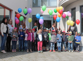 Auf dem Bild sind die Kinder und Erwachsene mit Luftballons zu sehen