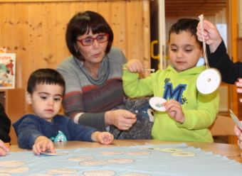 Auf dem Bild sind Kinder, die am Tisch gemeinsam mit Erwachsenen spielen, zu sehen