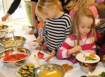 Auf dem Bild sind einige Kinder am Buffet zu sehen