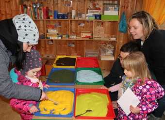 Auf dem Bild sind Kinder beim Basteln von Sandbilder zu sehen