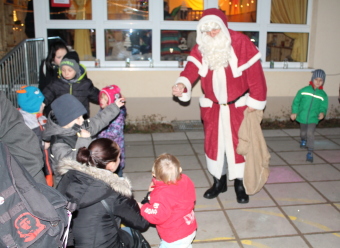 Auf dem Bild sind Kinder und Erwachsene zu sehen, die mit dem Weihnachtsmann sprechen