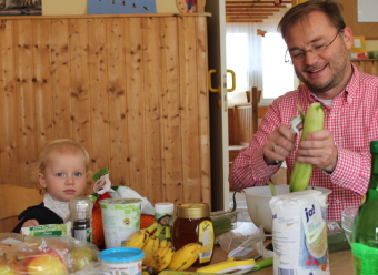 Auf dem Bild ist ein Vater, der Salat macht, mit seiner Tochter zu sehen