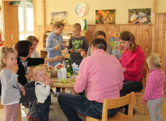 Auf dem Bild sind mehrere Erwachsene und Kinder an einem Tisch zu sehen