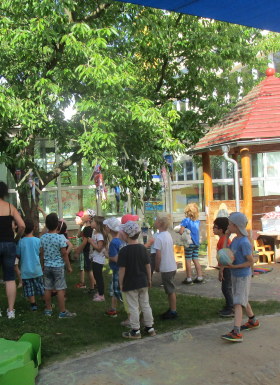 Die Kinder bestaunen den Zuckertütenbaum im kleinen Garten.