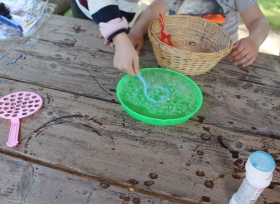 Kinderhände hantieren an Seifen-Blasen-Schale