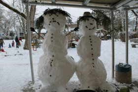 Zwei riesengroße Schneemänner, einer mit lachendem Gesicht, einer mit traurigem Gesicht